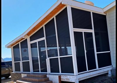Screened porch exterior with steps on sunny day.