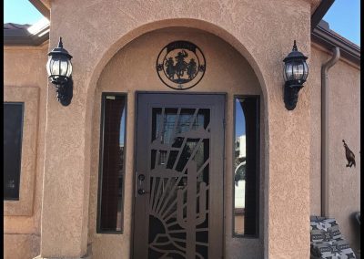 Stucco home entrance with decorative metal door and lanterns.