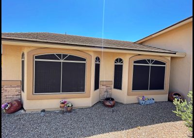 Stucco house exterior with decorative windows and welcome sign.