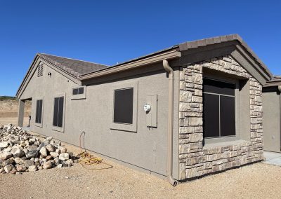 Beige house with stone accent under a clear blue sky.