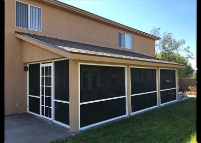 Two-story house with screened patio enclosure.