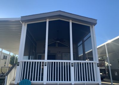 Screened porch with white railing on sunny day.