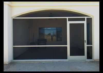 Screened patio entrance with barbecue grill and open door.
