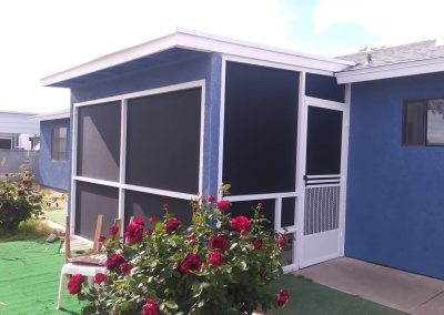 Blue house with screened porch and roses.