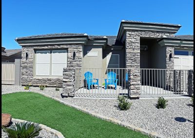 Modern house with manicured lawn and blue patio chairs.
