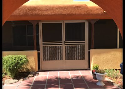 Southwestern-style home entryway with arch and tiled path.