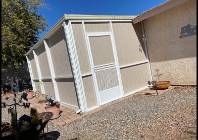 Backyard shed next to a house on sunny day.