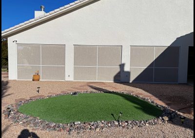 House exterior with triple garage doors and artificial lawn.