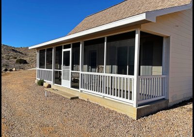 House with screened porch in desert setting.