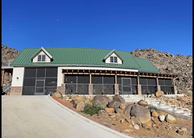 Mountain lodge with green roof under clear blue sky.
