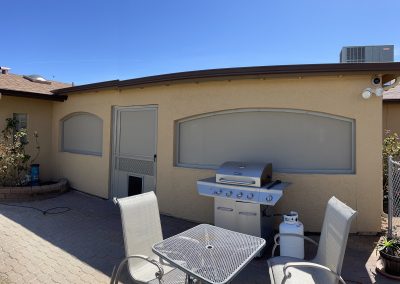 Backyard patio with grill and outdoor furniture.