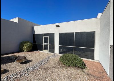 Modern home exterior with large windows and desert landscaping.