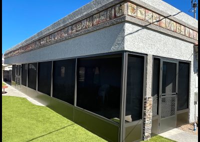 Modern building with green artificial turf under blue sky.