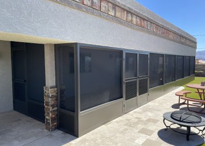 Outdoor covered patio with seating and screen doors.